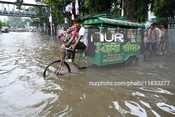 Vehicles and rickshaws try to drive with passengers through the waterlogged streets of Dhaka, Bangladesh, on October 3, 2024, after heavy mo...