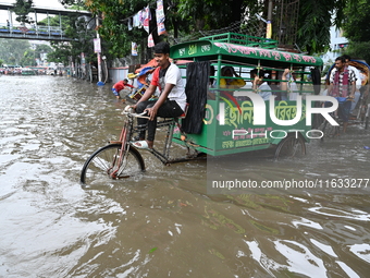 Vehicles and rickshaws try to drive with passengers through the waterlogged streets of Dhaka, Bangladesh, on October 3, 2024, after heavy mo...