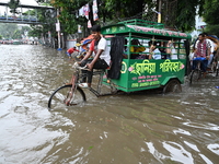 Vehicles and rickshaws try to drive with passengers through the waterlogged streets of Dhaka, Bangladesh, on October 3, 2024, after heavy mo...