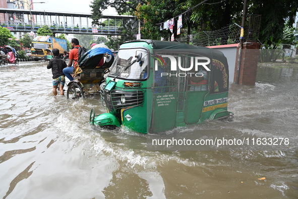 Vehicles and rickshaws try to drive with passengers through the waterlogged streets of Dhaka, Bangladesh, on October 3, 2024, after heavy mo...