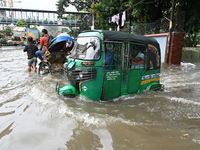 Vehicles and rickshaws try to drive with passengers through the waterlogged streets of Dhaka, Bangladesh, on October 3, 2024, after heavy mo...