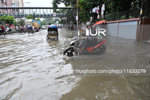 Vehicles and rickshaws try to drive with passengers through the waterlogged streets of Dhaka, Bangladesh, on October 3, 2024, after heavy mo...