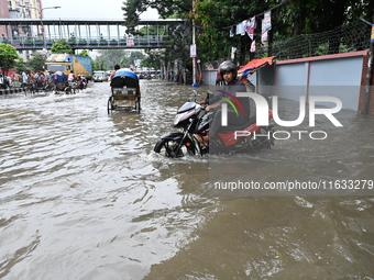 Vehicles and rickshaws try to drive with passengers through the waterlogged streets of Dhaka, Bangladesh, on October 3, 2024, after heavy mo...