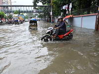 Vehicles and rickshaws try to drive with passengers through the waterlogged streets of Dhaka, Bangladesh, on October 3, 2024, after heavy mo...