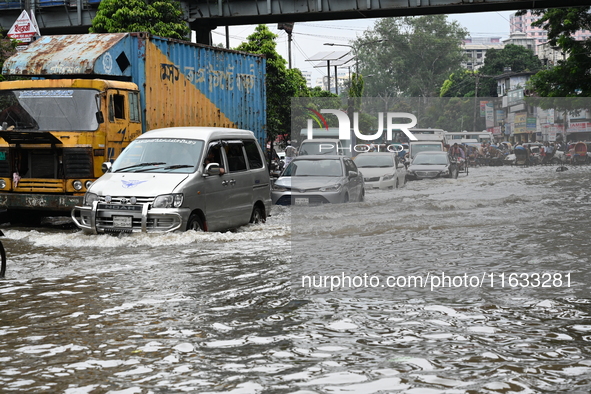 Vehicles and rickshaws try to drive with passengers through the waterlogged streets of Dhaka, Bangladesh, on October 3, 2024, after heavy mo...