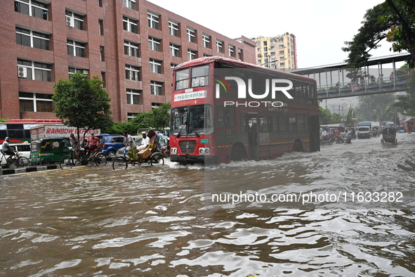 Vehicles and rickshaws try to drive with passengers through the waterlogged streets of Dhaka, Bangladesh, on October 3, 2024, after heavy mo...