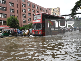 Vehicles and rickshaws try to drive with passengers through the waterlogged streets of Dhaka, Bangladesh, on October 3, 2024, after heavy mo...