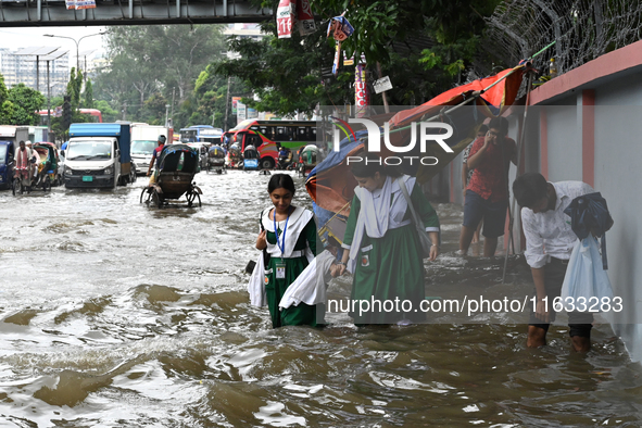 Vehicles and rickshaws try to drive with passengers through the waterlogged streets of Dhaka, Bangladesh, on October 3, 2024, after heavy mo...