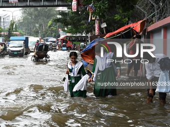 Vehicles and rickshaws try to drive with passengers through the waterlogged streets of Dhaka, Bangladesh, on October 3, 2024, after heavy mo...