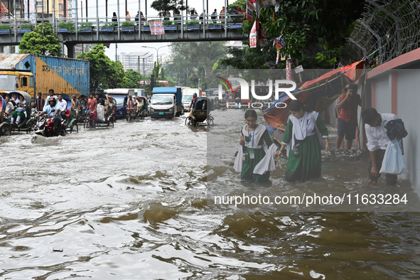 Vehicles and rickshaws try to drive with passengers through the waterlogged streets of Dhaka, Bangladesh, on October 3, 2024, after heavy mo...