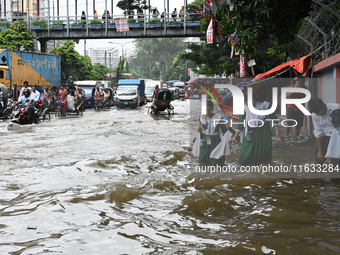 Vehicles and rickshaws try to drive with passengers through the waterlogged streets of Dhaka, Bangladesh, on October 3, 2024, after heavy mo...