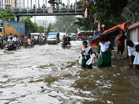 Vehicles and rickshaws try to drive with passengers through the waterlogged streets of Dhaka, Bangladesh, on October 3, 2024, after heavy mo...