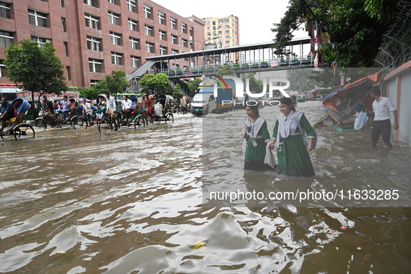 Vehicles and rickshaws try to drive with passengers through the waterlogged streets of Dhaka, Bangladesh, on October 3, 2024, after heavy mo...