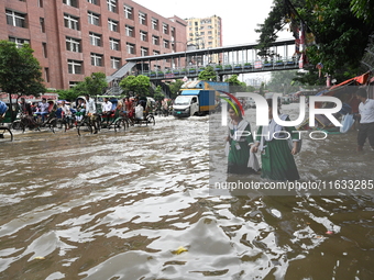 Vehicles and rickshaws try to drive with passengers through the waterlogged streets of Dhaka, Bangladesh, on October 3, 2024, after heavy mo...