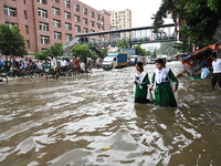 Vehicles and rickshaws try to drive with passengers through the waterlogged streets of Dhaka, Bangladesh, on October 3, 2024, after heavy mo...