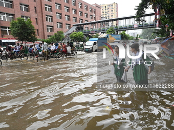 Vehicles and rickshaws try to drive with passengers through the waterlogged streets of Dhaka, Bangladesh, on October 3, 2024, after heavy mo...