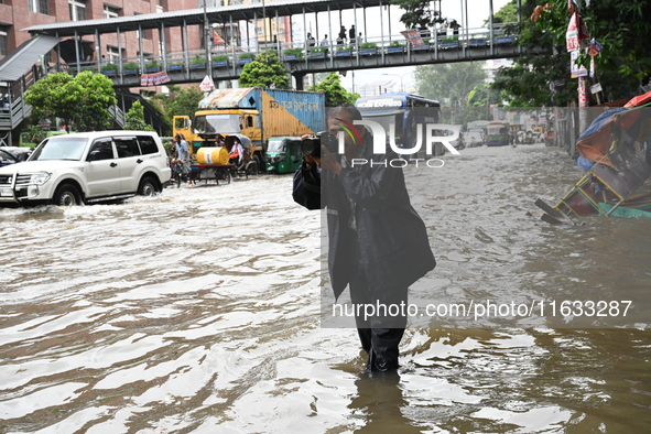 Vehicles and rickshaws try to drive with passengers through the waterlogged streets of Dhaka, Bangladesh, on October 3, 2024, after heavy mo...