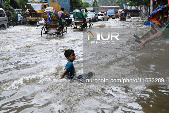 Vehicles and rickshaws try to drive with passengers through the waterlogged streets of Dhaka, Bangladesh, on October 3, 2024, after heavy mo...