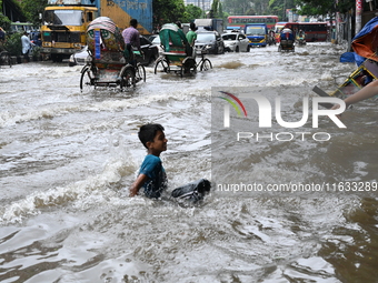 Vehicles and rickshaws try to drive with passengers through the waterlogged streets of Dhaka, Bangladesh, on October 3, 2024, after heavy mo...