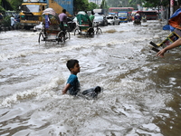 Vehicles and rickshaws try to drive with passengers through the waterlogged streets of Dhaka, Bangladesh, on October 3, 2024, after heavy mo...