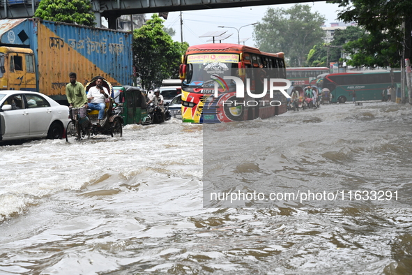 Vehicles and rickshaws try to drive with passengers through the waterlogged streets of Dhaka, Bangladesh, on October 3, 2024, after heavy mo...