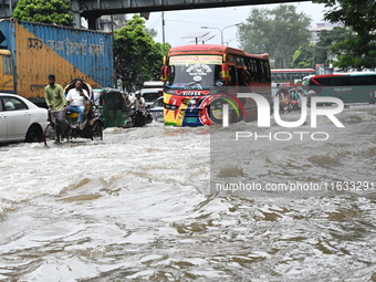 Vehicles and rickshaws try to drive with passengers through the waterlogged streets of Dhaka, Bangladesh, on October 3, 2024, after heavy mo...