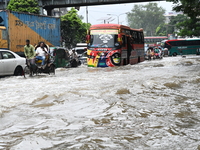 Vehicles and rickshaws try to drive with passengers through the waterlogged streets of Dhaka, Bangladesh, on October 3, 2024, after heavy mo...