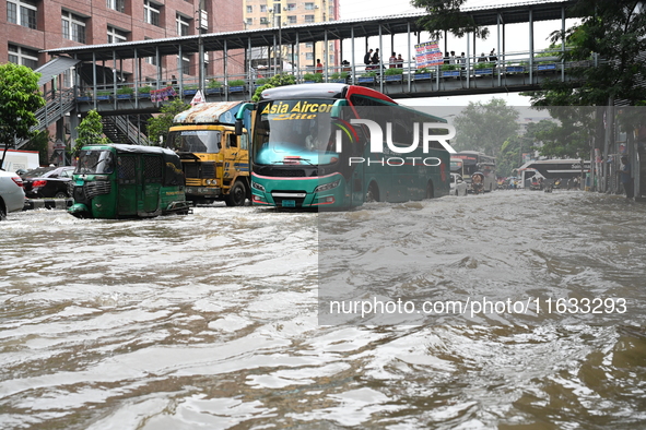 Vehicles and rickshaws try to drive with passengers through the waterlogged streets of Dhaka, Bangladesh, on October 3, 2024, after heavy mo...