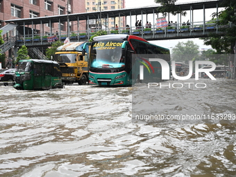 Vehicles and rickshaws try to drive with passengers through the waterlogged streets of Dhaka, Bangladesh, on October 3, 2024, after heavy mo...