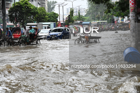 Vehicles and rickshaws try to drive with passengers through the waterlogged streets of Dhaka, Bangladesh, on October 3, 2024, after heavy mo...