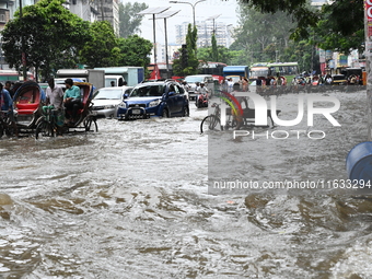 Vehicles and rickshaws try to drive with passengers through the waterlogged streets of Dhaka, Bangladesh, on October 3, 2024, after heavy mo...