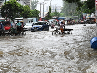 Vehicles and rickshaws try to drive with passengers through the waterlogged streets of Dhaka, Bangladesh, on October 3, 2024, after heavy mo...