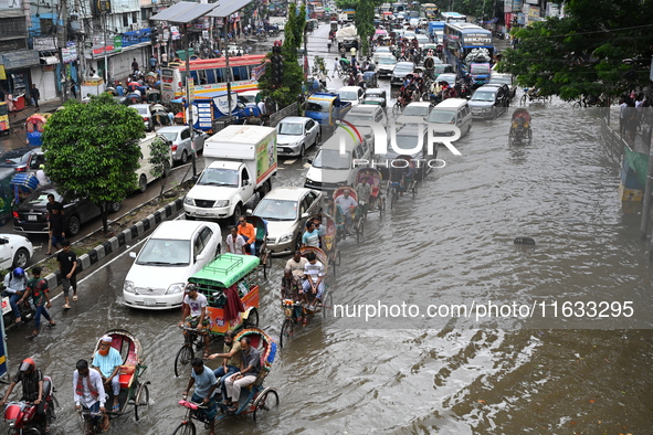 Vehicles and rickshaws try to drive with passengers through the waterlogged streets of Dhaka, Bangladesh, on October 3, 2024, after heavy mo...