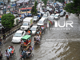 Vehicles and rickshaws try to drive with passengers through the waterlogged streets of Dhaka, Bangladesh, on October 3, 2024, after heavy mo...