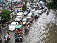 Vehicles and rickshaws try to drive with passengers through the waterlogged streets of Dhaka, Bangladesh, on October 3, 2024, after heavy mo...