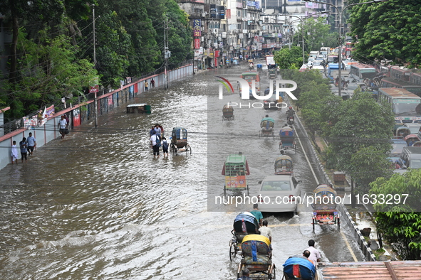 Vehicles and rickshaws try to drive with passengers through the waterlogged streets of Dhaka, Bangladesh, on October 3, 2024, after heavy mo...