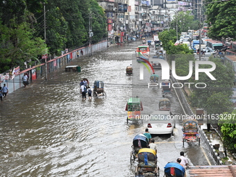 Vehicles and rickshaws try to drive with passengers through the waterlogged streets of Dhaka, Bangladesh, on October 3, 2024, after heavy mo...