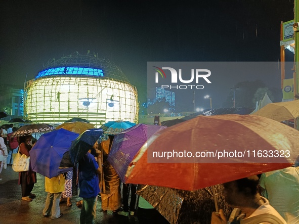 Visitors hold umbrellas amid heavy rain while visiting a puja pandal ahead of the Durga Puja festival in Kolkata, India, on October 3, 2024....