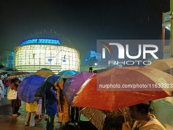 Visitors hold umbrellas amid heavy rain while visiting a puja pandal ahead of the Durga Puja festival in Kolkata, India, on October 3, 2024....