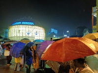 Visitors hold umbrellas amid heavy rain while visiting a puja pandal ahead of the Durga Puja festival in Kolkata, India, on October 3, 2024....