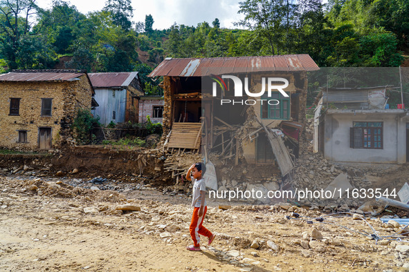 A child walks in front of her home damaged by flooding from the Salamdo River in Patikharka, Kavrepalanchok District, Nepal, on October 3, 2...