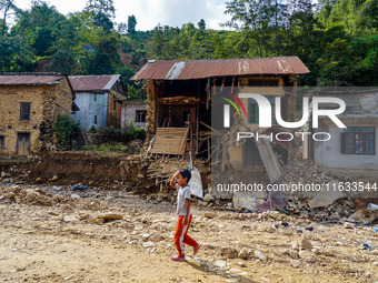 A child walks in front of her home damaged by flooding from the Salamdo River in Patikharka, Kavrepalanchok District, Nepal, on October 3, 2...