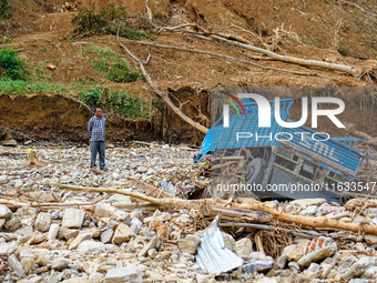 A man stands looking at his vehicle damaged by flooding from the Salamdo River in Patikharka, Kavrepalanchok District, Nepal, on October 3,...