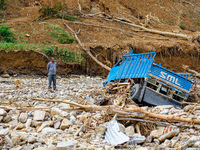 A man stands looking at his vehicle damaged by flooding from the Salamdo River in Patikharka, Kavrepalanchok District, Nepal, on October 3,...