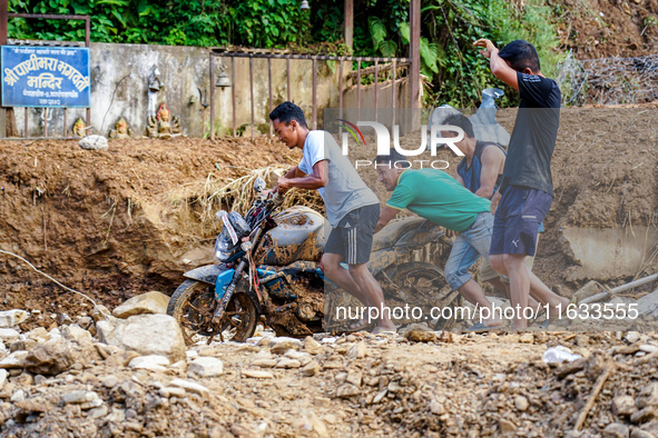 People pull a flood-damaged bike from the Salamdo River in Patikharka, Kavrepalanchok District, Nepal, on October 3, 2024. 