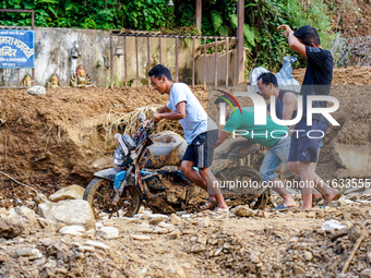 People pull a flood-damaged bike from the Salamdo River in Patikharka, Kavrepalanchok District, Nepal, on October 3, 2024. (