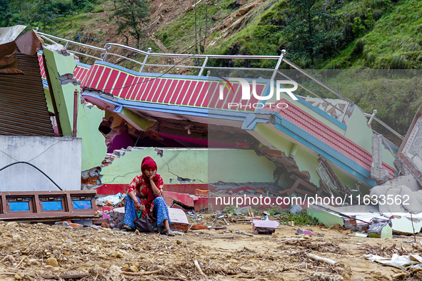 A woman sits in front of her flood-damaged home from the Salamdo River in Patikharka, Kavrepalanchok District, Nepal, on October 03, 2024. A...