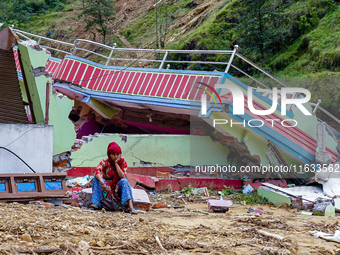 A woman sits in front of her flood-damaged home from the Salamdo River in Patikharka, Kavrepalanchok District, Nepal, on October 03, 2024. A...