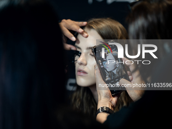 Someone takes a photo of a model with a mobile phone backstage before she walks on the runway during Day 2 of Bangkok International Fashion...