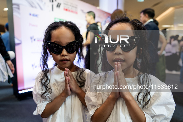 Young twin models give a 'Wai' greeting on the red carpet after walking on the runway during Day 2 of Bangkok International Fashion Week at...